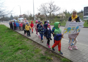 Dzieci maszerują ulicami osiedla z transparentami ekologicznymi.